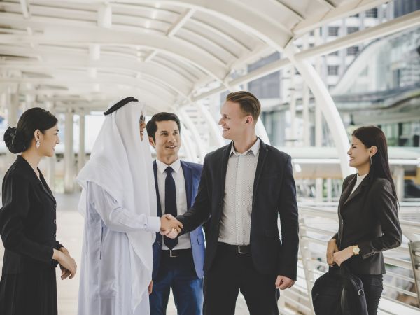 Portrait of business partners greeting one another by handshaking on the way to office.